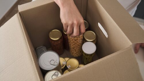 Hand putting jars of food in a box