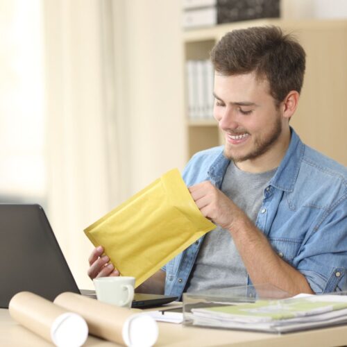 Man smiles as he puts something into small packing envelope