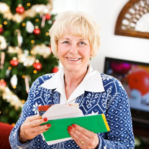 Woman smiles as she reads her mails and Christmas cards